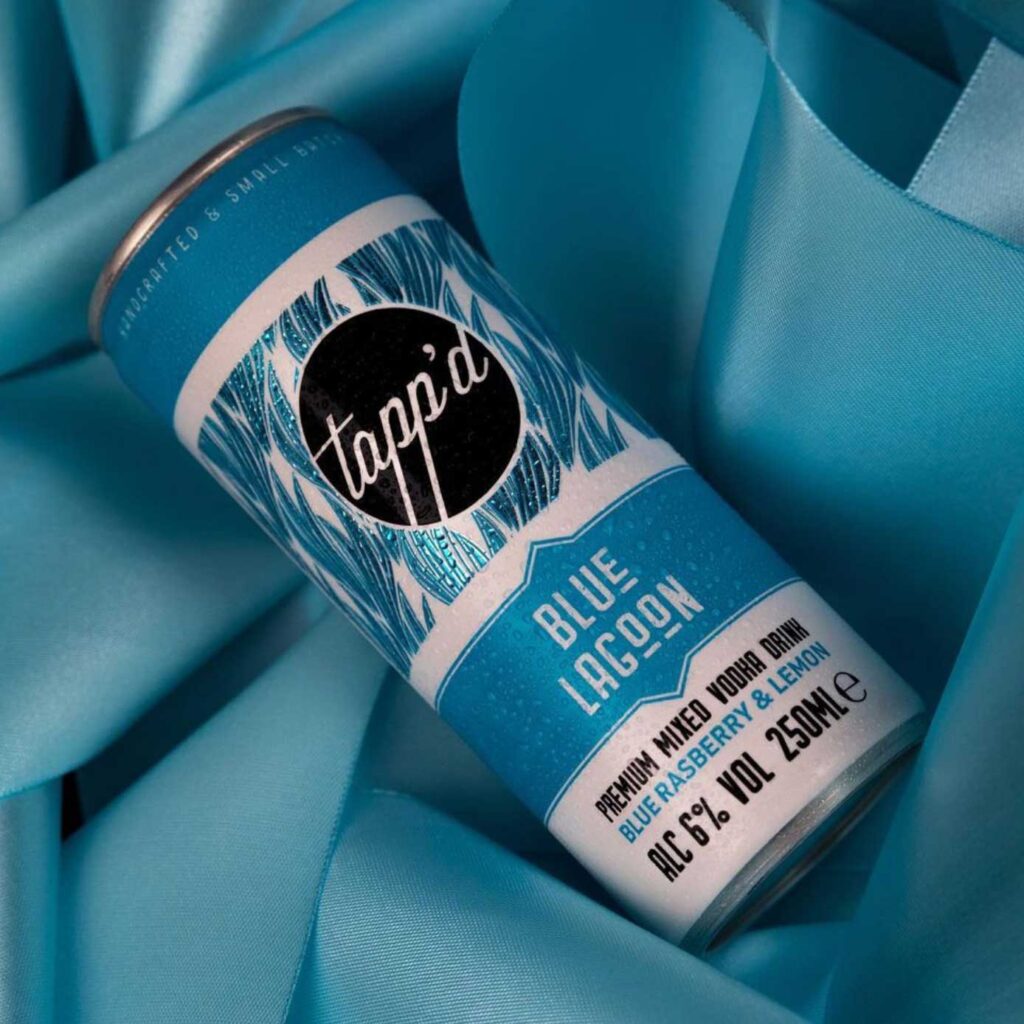 Can of 'Blue Lagoon' mixed vodka drink on blue satin fabric